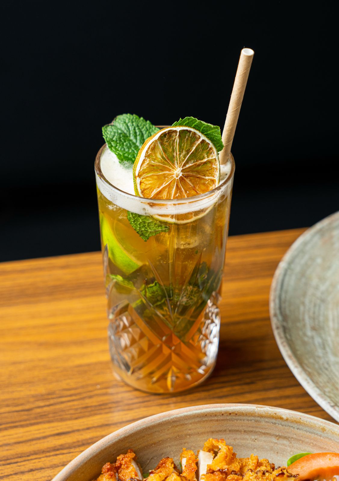 Cocktail ambré servi au bar du Roi de Pique, lumière chaude, atmosphère de soirée